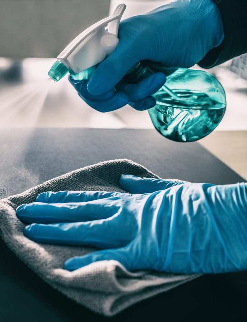 surface sanitizing against covid 19 outbreak. home cleaning spraying antibacterial spray bottle disinfecting against coronavirus wearing nitrile gloves. sanitize hospital surfaces prevention.